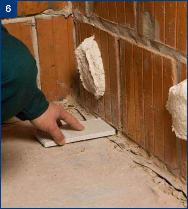 Fot 6: Po nałożeniu placków przyklejamy płytę do ściany pamiętając o podkładkach dystansowych od podłoża (można posłużyć się kawałkami płyt gipsowych).