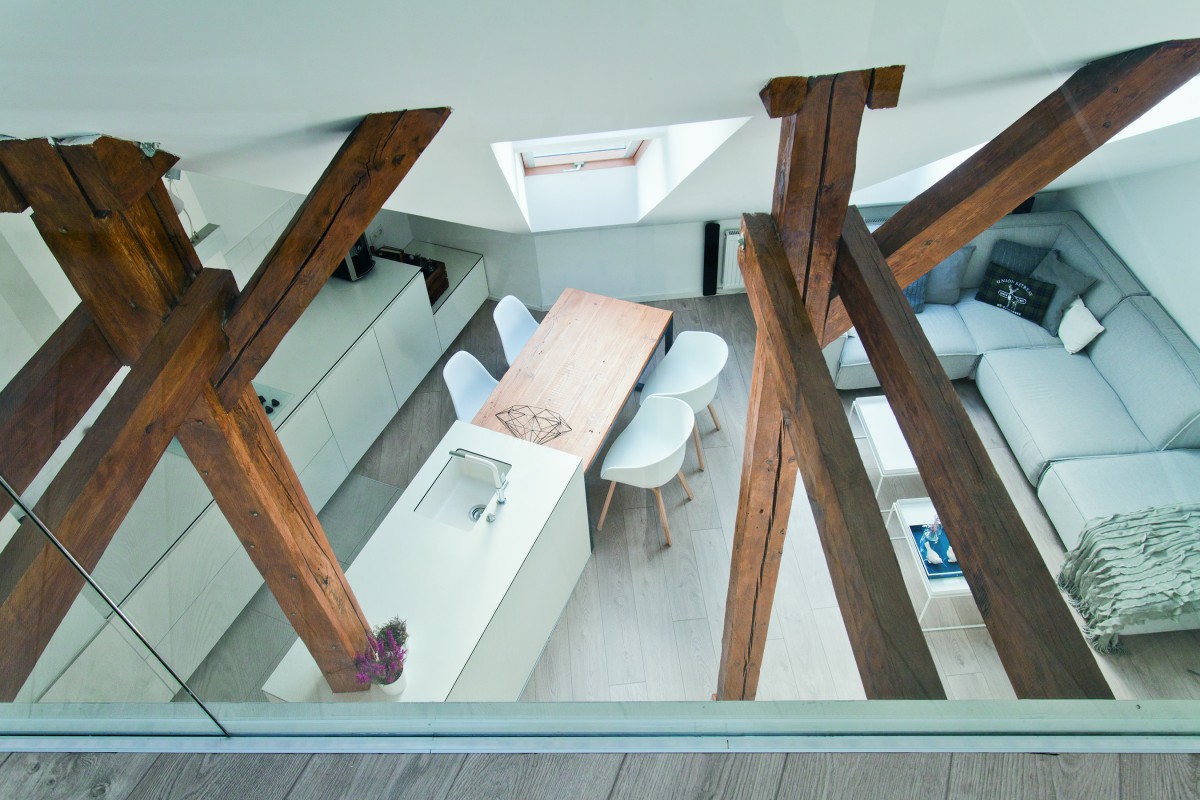 Drewniane okna FAKRO idealnie komponują się z belkami konstrukcyjnymi oddzielającymi kuchnię od przestrzeni wypoczynkowej na poddaszu. Fot. Fakro